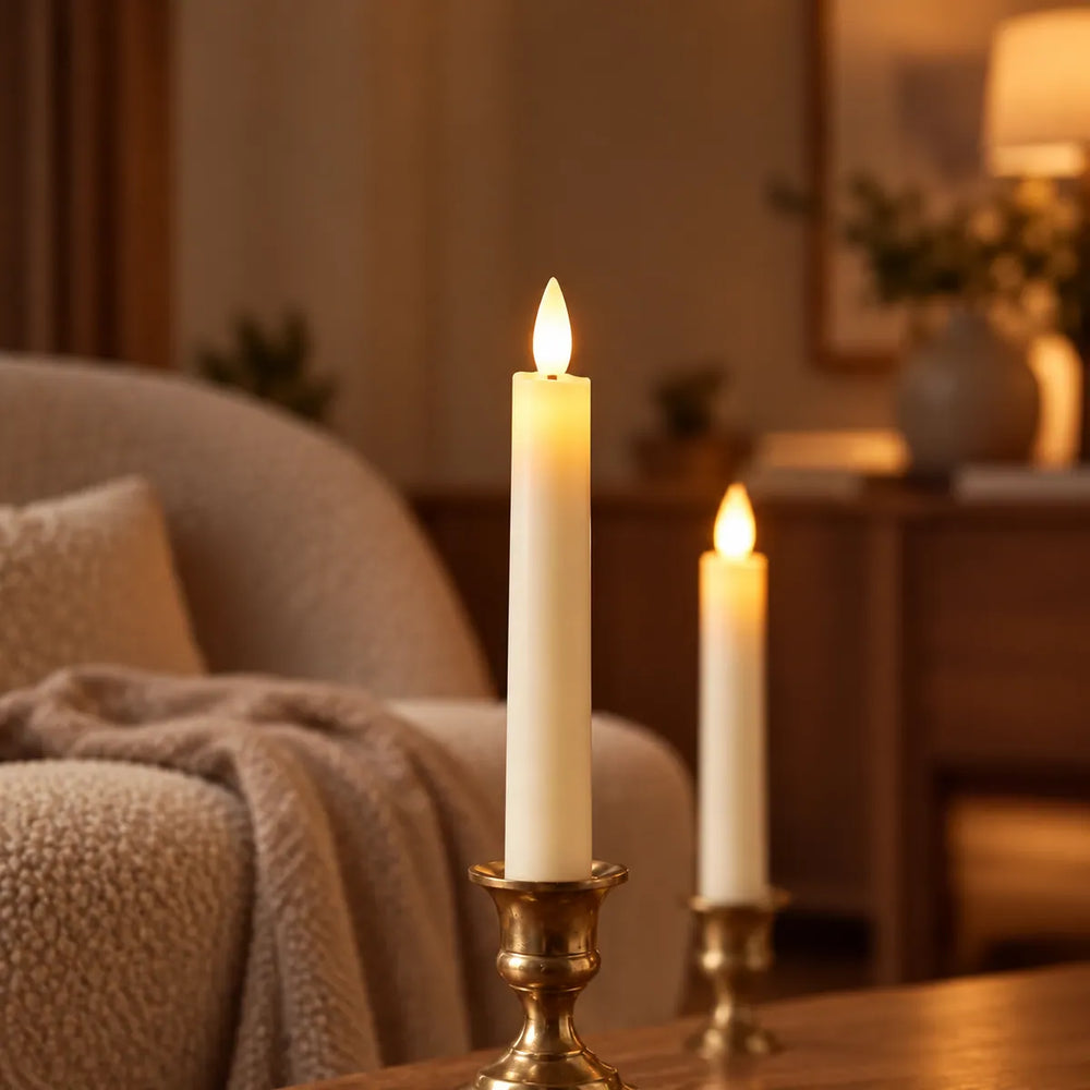 Close-up van een vlamloze Wove Luma LED-dinerkaars met warme gloed in een messing kandelaar naast een fauteuil