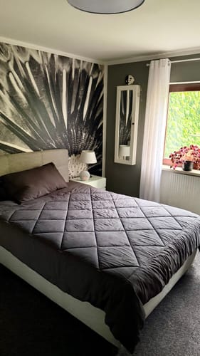 Grijs Wove-dekbed op een tweepersoonsbed voor een donkere muur met fotobehang