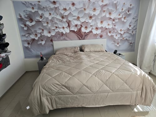 Beige Wove-dekbed op een groot bed in een logeerkamer met bloemenbehang