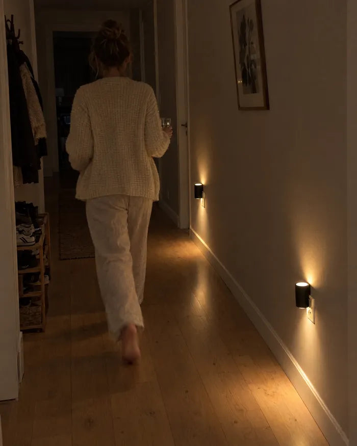 Vrouw loopt door een donkere gang waar wandlampen bij de vloer branden