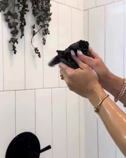 Klant gebruikt de Wove-handdoek op haar rug in de douche