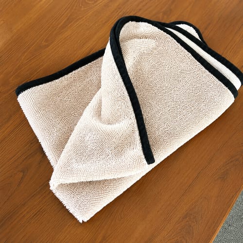 Beige Wove microvezeldoek gevouwen op een houten blad