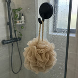 Zwarte Wove-haak op een glazen douchewand met een beige spons